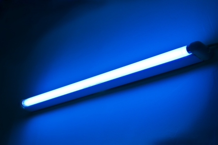 One fluorescent lamp shining on blue colored wallの写真素材