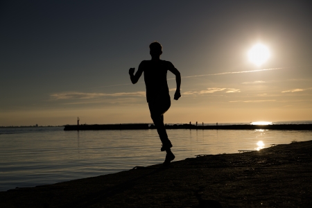 Sportsman making jumpy movement at beach late eveningの写真素材