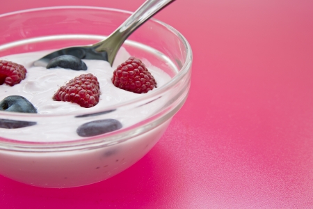 Bowl with jogurt and spoon on pink backgroundの写真素材