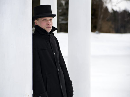 Man in black hat relies on white column