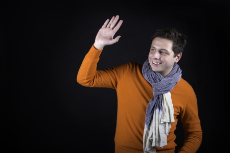 Man on black background greeting someone outside frame.の写真素材