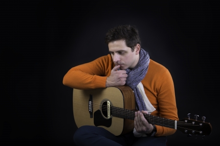 Thinking man on background posing with acoustic guitar.の写真素材