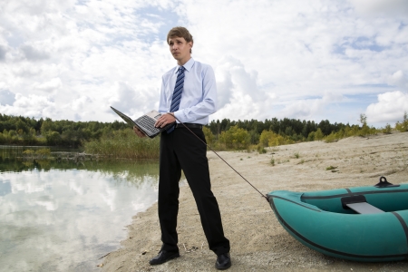 Dressed man drags boat over sandy lake shoreの写真素材