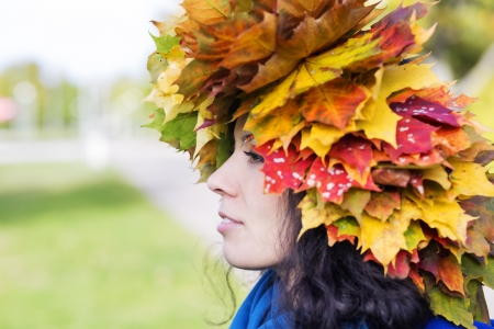 Woman with maple leaves on head from sideの写真素材
