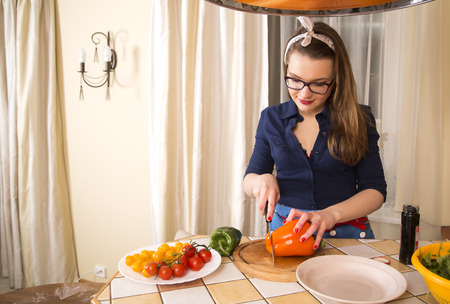 Woman at sexy suit cuts paprika for pizzaの写真素材