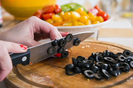 Woman soft fingers cut black olives to slicesの写真素材