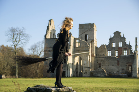 Witch with pale skin with broom on stoneの写真素材