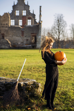 Witch with pale skin look at orange pumpkinの写真素材