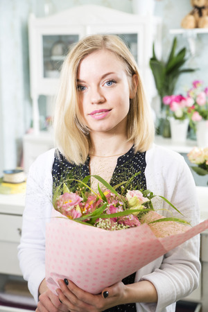 Smiling female holds a bunch of flowersの写真素材
