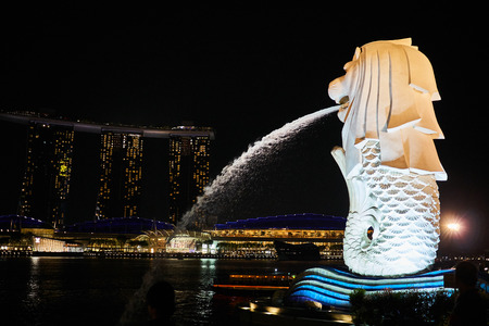 The litle merlion of Singapore is spewing a stream into the river at night.のeditorial素材