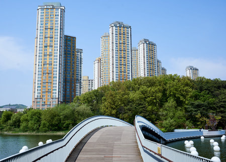 A bridge over a lake leading to a hill in the Gwangkyo Lake Park and nearby apartments in South...