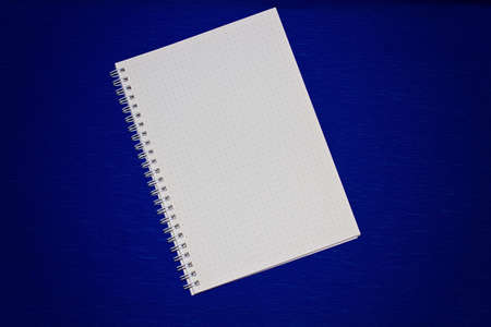 A notebook on a spring with sheets to a point on a blue backgroundの写真素材