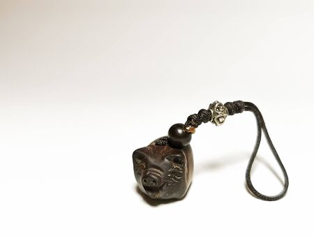 A pig is a symbol of wealth in the east. A close-up of a wooden Korean pig-shaped netsuke with decorated string. Space for your text.の写真素材