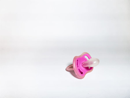 Pink pacifier on a white background.