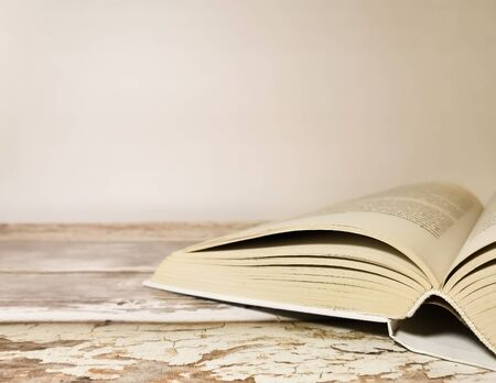 Opened book on a wooden table. White background. Space for your text. Image with selective focus and with toning.の写真素材