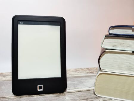 E-book and a stack of paper books. The choice between paper and e-book. Space for your text.の写真素材