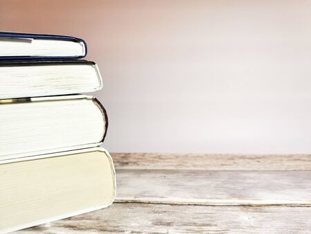 Close-up of a stack of four books on a wooden table and white background. Space for your text. Image with toning.の写真素材