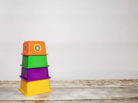 Educational toy for children - multi-colored pyramid on a wooden table and white background. Space for your text.の写真素材