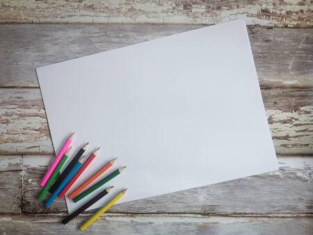 Frame for your text - white sheet of paper with pencils on old wooden boards. Drawing with children. Space for your text.の写真素材