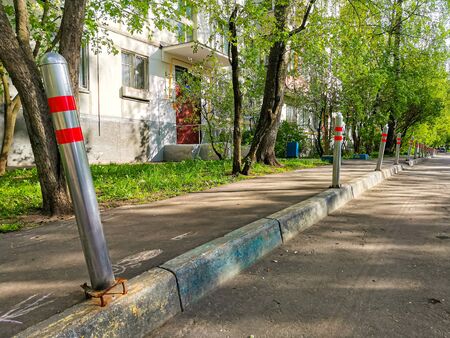 Old asphalt, curb and parking posts in the courtyard of an apartment building. Arrangement of courtyards, replacement of pavement, traffic safety and parking rules.の写真素材