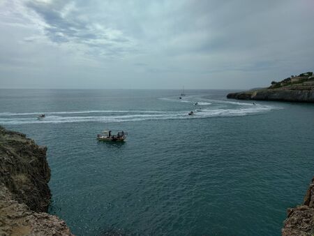 Boats and jet skis at high speed in the bay in the bay of Cala Domingos on the island of Mallorca, Spain. It's a nasty day. Water sports and entertainment. Water transport. Traveling concept.の写真素材