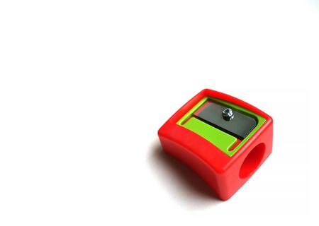 Red pencil sharpener with a green element on a white background. Close-up, space for text.の写真素材