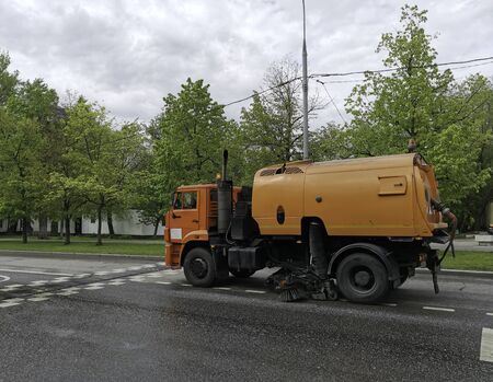 Orange sweeper machine (street sweeper) cleans city road.の写真素材