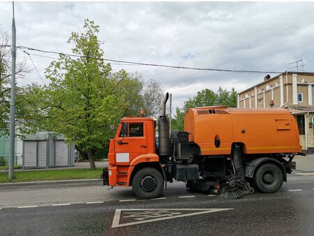 Orange sweeper machine (street sweeper) cleans city road.の写真素材