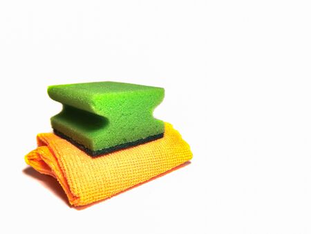 Green sponge for washing dishes on an orange cleaning cloth isolated on white background. Cleaning, household, kitchen utensils.の写真素材