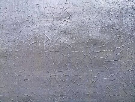 Texture of gray uneven painted wall with cracks and glows. Cracked silver metallic paint, grunge. Background for design.の写真素材