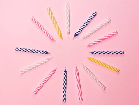 Multi-colored birthday candles on a pink background. Blank for greeting card, background for a birthday invitation, a symbol of the holiday and party.の写真素材