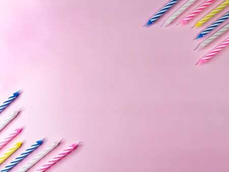 Multi-colored birthday candles on a pink background. Background for birthday or anniversary card or invitation card. Stock photo with empty space for text and design.の写真素材