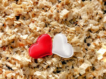 Closeup of red and white hearts against the background of wooden sawdust in sunny color. Ð¡ard for romantic greetings, background for lovers. The concept of love and relationships. Selective focus.の写真素材