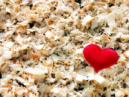 Closeup of red heart on the background of wooden sawdust in sunny color. Ð¡ard for romantic congratulations, declarations of love. The concept is natural, eco-friendly. Selective focus.の写真素材