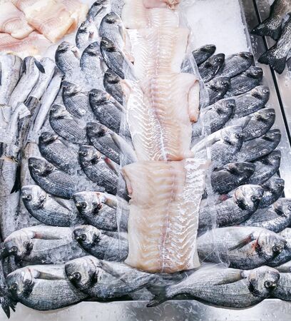 Fresh fish counter at the market. Freshly baked dorada and cod fillet neatly laid out on ice. Natural products, proper nutrition, fish diet.の写真素材