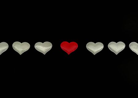 White hearts in a row with a central red heart on a black background. Concept: you are not like everyone else, special, true love. Blank for card with your text.の写真素材