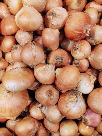 A solid background of unpeeled onions at the market. Popular and affordable vegetables in the supermarket, a source of vitamin C. The most popular vegetable in the world. View from above.の写真素材