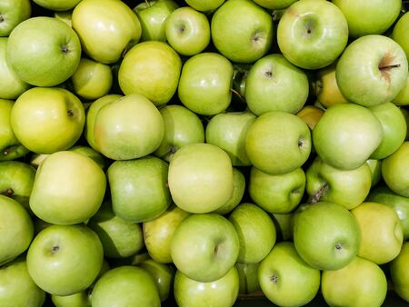 Solid background of green apples in a crate. Many organic Granny Smith apples. Healthy and affordable fruits in the supermarket, source of vitamin C. Pattern for design. View from above.の写真素材
