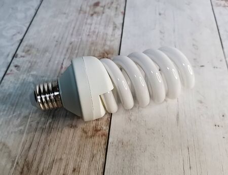 Energy saving light bulb close-up on a background of a light wooden tabletop. Green energy consumption, saving resources and finances.の写真素材