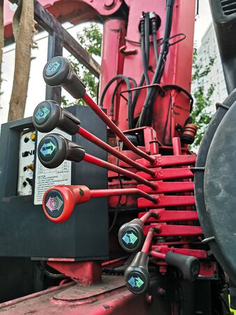 Image of hydraulic control valve on the side of the mobile crane. Red metal levers of control of an old truck crane.の写真素材
