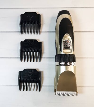 Electric pet clipper with plastic nozzles and ceramic knife on a light wooden background. Grooming tools for the hygienic care of pets cats and dogs.の写真素材