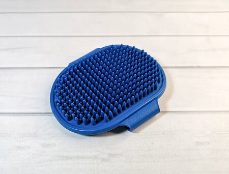 Soft blue rubber massage brush for animals. Pet care accessories. Hand-held massage brush to remove excess hair from dogs and cats during molting.の写真素材