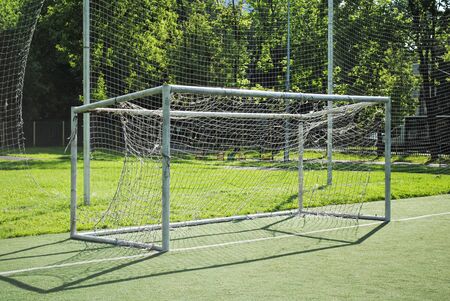 Soccer goal on a school soccer field on a sunny summer day. Amateur football, goal with a torn and dirty net.の写真素材