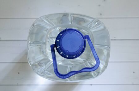 A large plastic water bottle on a light wooden floor background. View from above. A symbol of basic human resources. The problem of using plastic bottles and their recycling.の写真素材