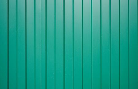 Galvanized iron fence with corrugated vertical stripes of green as fence wall. Vertical narrow lines. Bright color pattern for designers.の写真素材