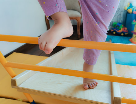 Legs of a todler climbing a frame a staircase of a home sports complex. Sports games with children...