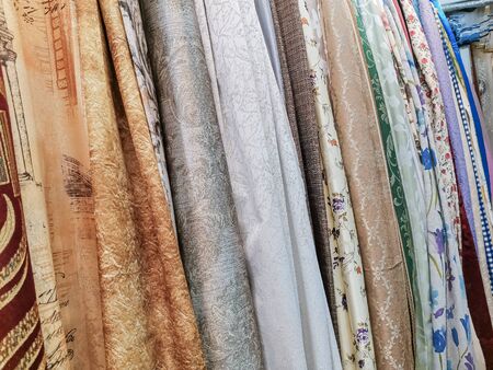 A showcase of a fabric store. Fabrics hang vertically for ease of choice by customers. Different textile textures and colors.の写真素材