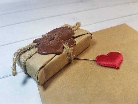Delivery box tied with twine with a wax seal with an envelope from craft paper with a red heart. Concept: free delivery, gifts, vintage souvenirs, Love message, letter of recognition.の写真素材
