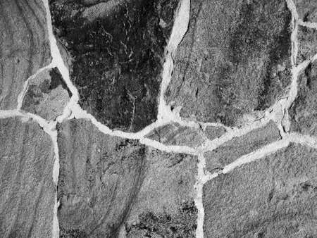 Close-up of a stone wall with uneven outlines and white seams. Black and white image. Part of wall, for background or textureの写真素材