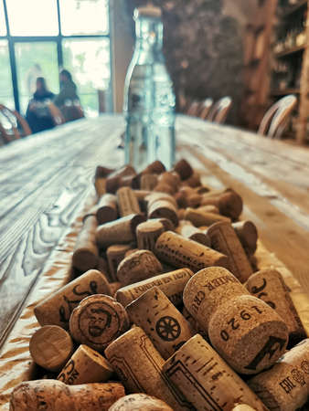Moscow / Russia - 07.18.2020: Close-up of wine corks on a wooden table and a glass bottle in the background. Wine bar interior element. Wine shop decoration details.のeditorial素材
